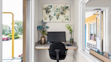 A home office with a desk, computer, chair, and decorative plants.
