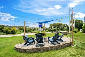 Un espace de détente circulaire avec des fauteuils Adirondack, un mur en pierre et un auvent bleu.