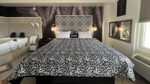 Un dormitorio con una cama grande, una bañera empotrada y un espejo fijado a la pared.