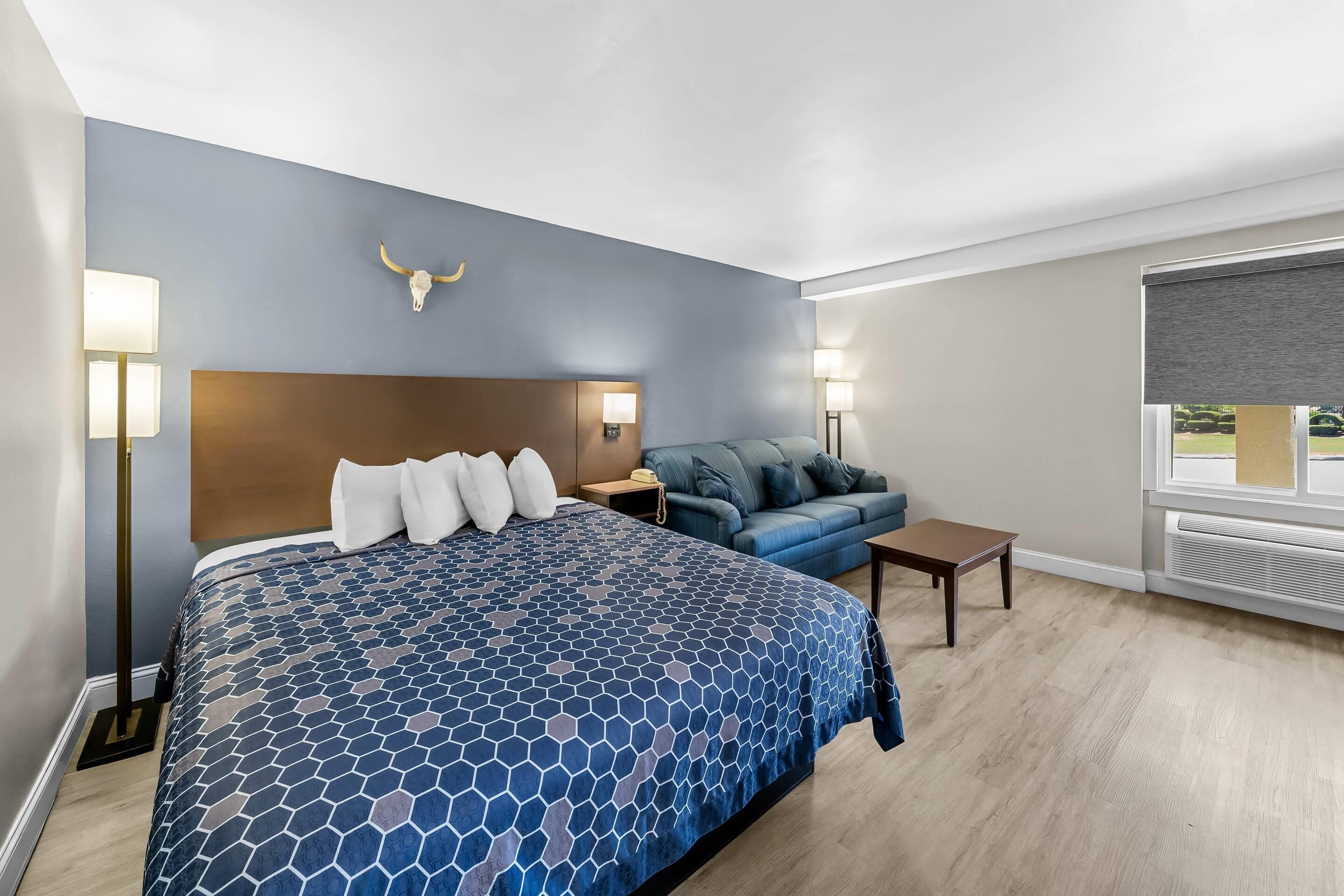 A hotel room with a large bed, a sofa, a desk, and a window with a view.