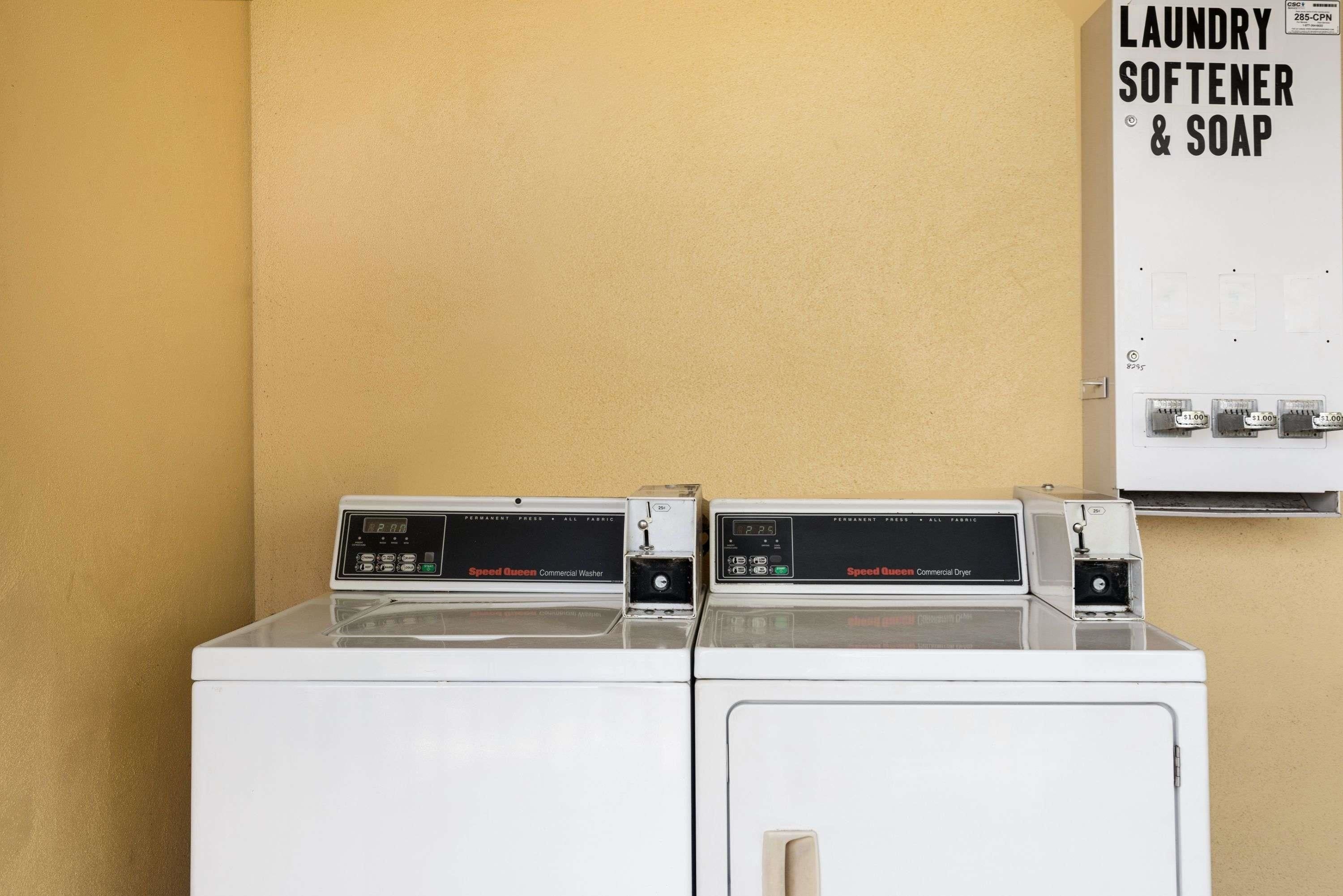 A laundry facility with two Speed Queen machines, one for washing and one for drying, and a sign indicating the availability of laundry softener and soap.