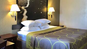 Una habitación de hotel con una cama, dos lámparas de noche, un escritorio y una silla.