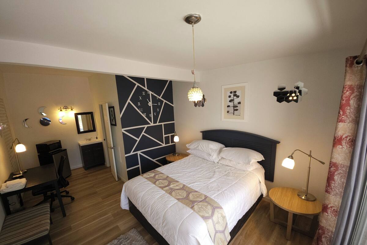 A modern bedroom with a large bed, a desk, and a chair.