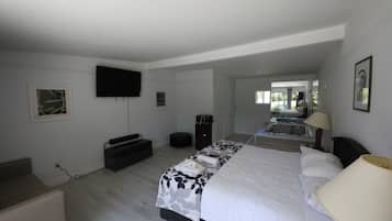 Quarto com uma cama grande, TV na parede, escrivaninha e uma cadeira.