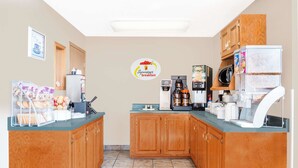 Una cocina compacta con armarios de madera, una cafetera, un microondas y un refrigerador.