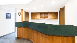 Una cocina con armarios de madera, encimera verde y un reloj en la pared.