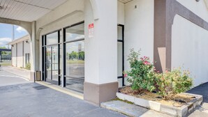 A building entrance with a glass door, a sign prohibiting entry, and a small flower bed.