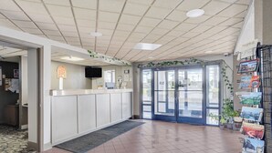 A reception area with a counter, a television, a door with glass panels, and a wall-mounted sign.