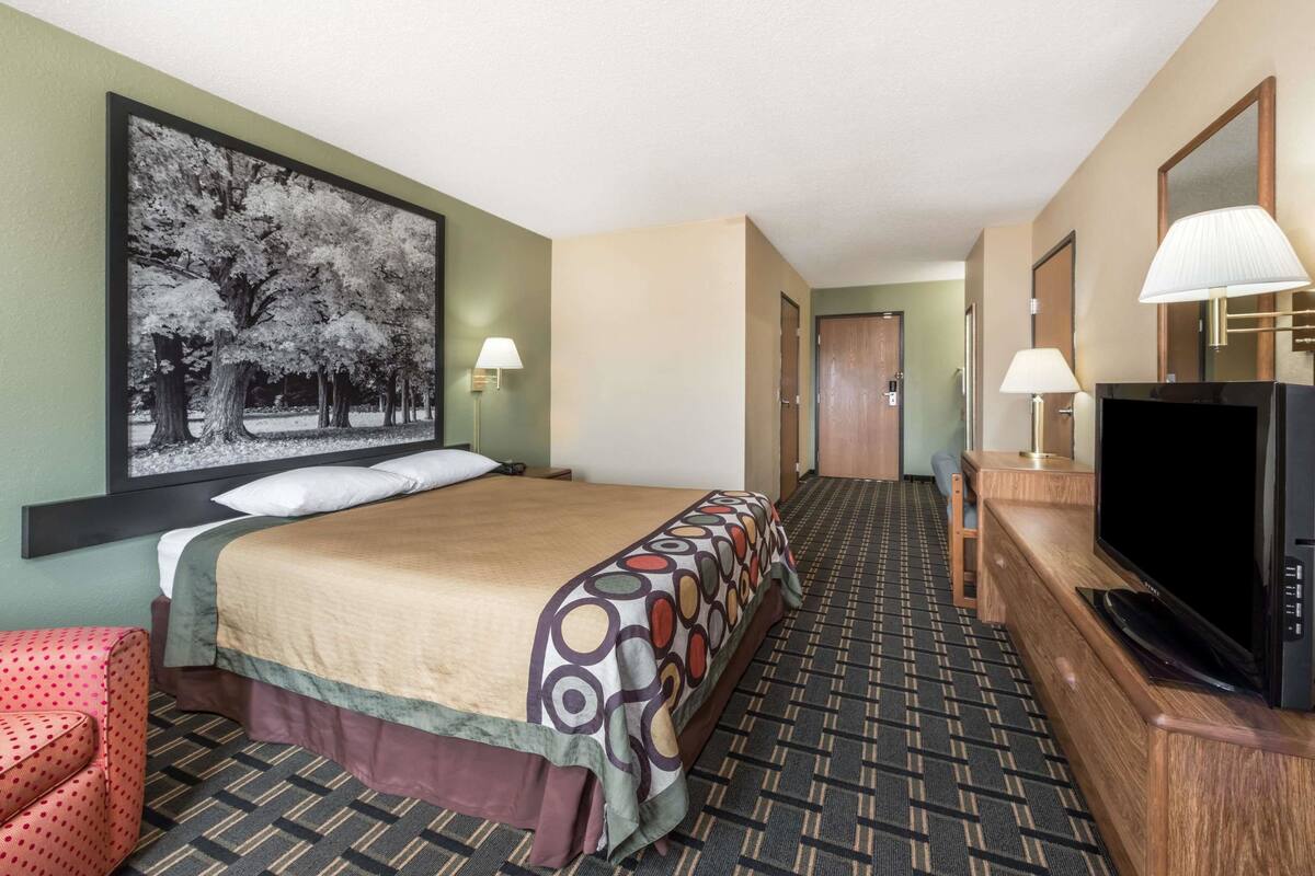 Una habitación de hotel con una cama, televisión, escritorio y una silla.