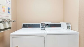 A laundry area with three washing machines and a dryer.