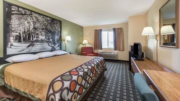 A hotel room with a large bed, a desk, a chair, a TV, and a window with curtains.