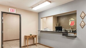 A reception area with a reception desk, a computer, a sewing machine, and an exit sign.