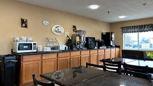 A breakfast area with a counter, microwave, coffee machine, and seating.