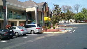 A hotel with a two-story structure, a covered outdoor area, and a parking lot with cars. - Super 8 by Wyndham Stafford (Stafford)