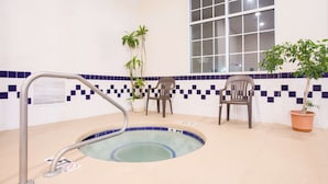 A small indoor pool with a blue tiled edge, two chairs, and potted plants. - SureStay Hotel by Best Western North Myrtle Beach (North Myrtle Beach)