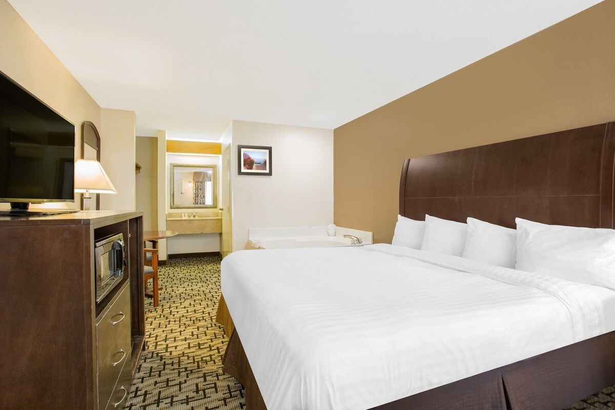 A hotel room with a large bed, a television, a desk, and a bathroom.