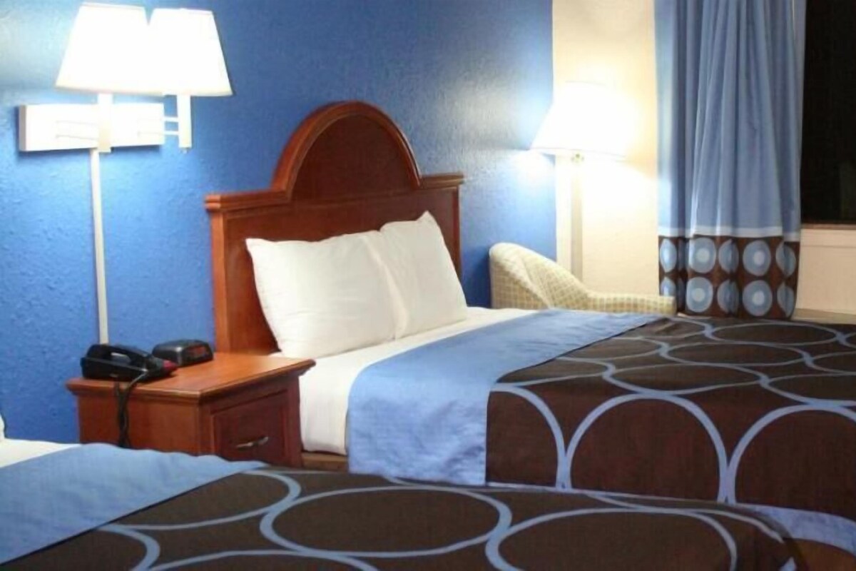 Habitación de hotel con cama, lámparas de noche, teléfono y ventana con cortinas.