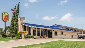 Een Super 8 motel met een blauw dak, grote ramen en een vlaggenmast met de Amerikaanse vlag.