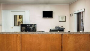 Een keuken met een aanrecht, een koffiezetapparaat, een magnetron en een aan de muur bevestigde televisie.