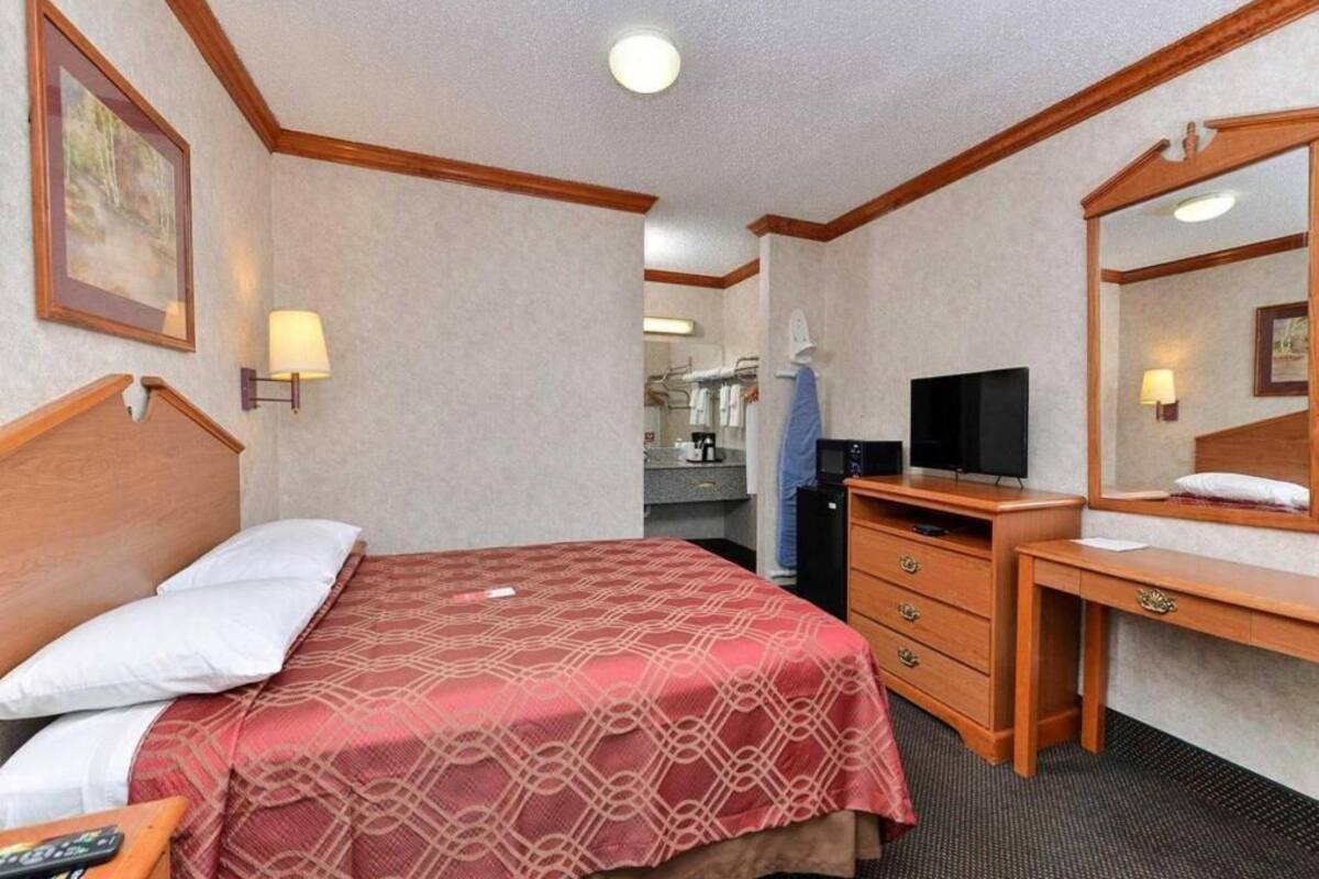 Une chambre d’hôtel avec un lit, un bureau, une télévision et un miroir.