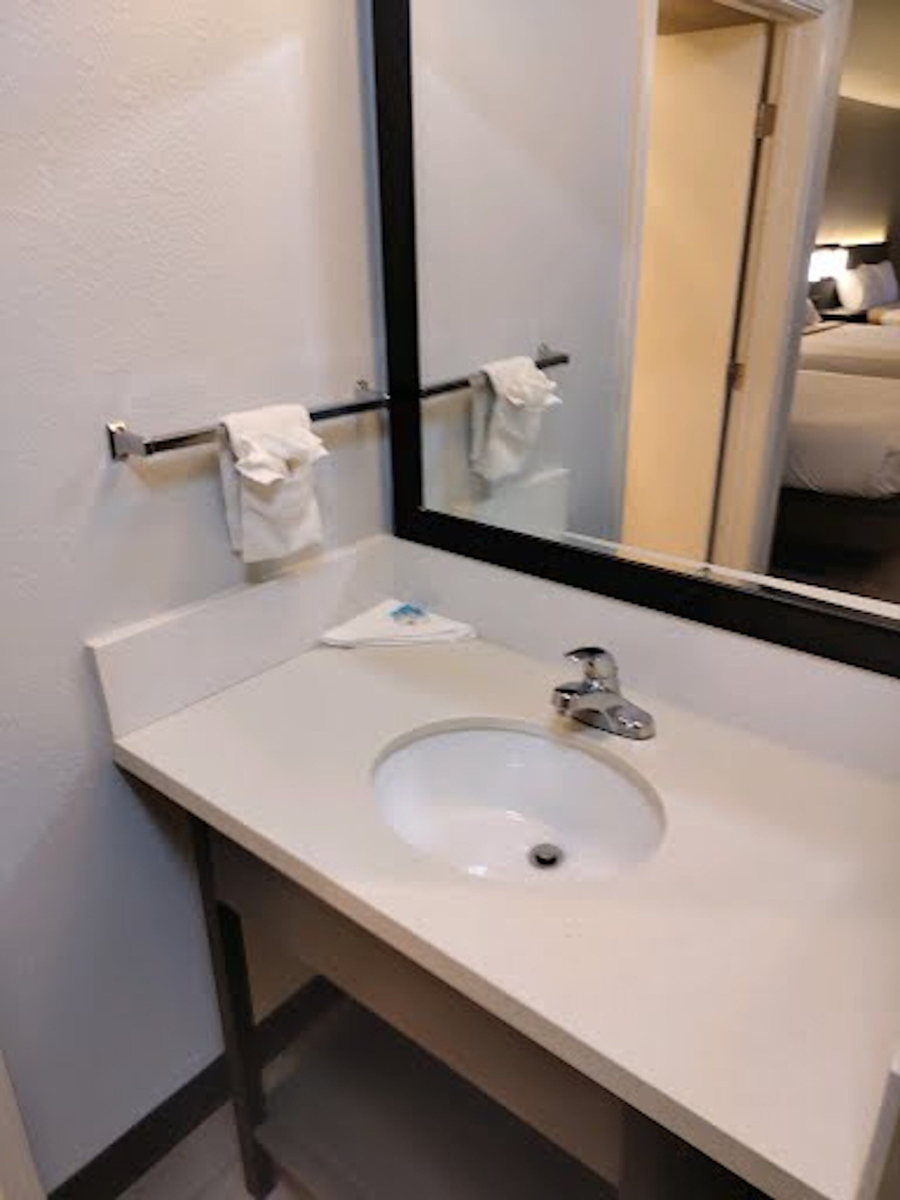 A bathroom with a white sink, a mirror, and a towel rack.