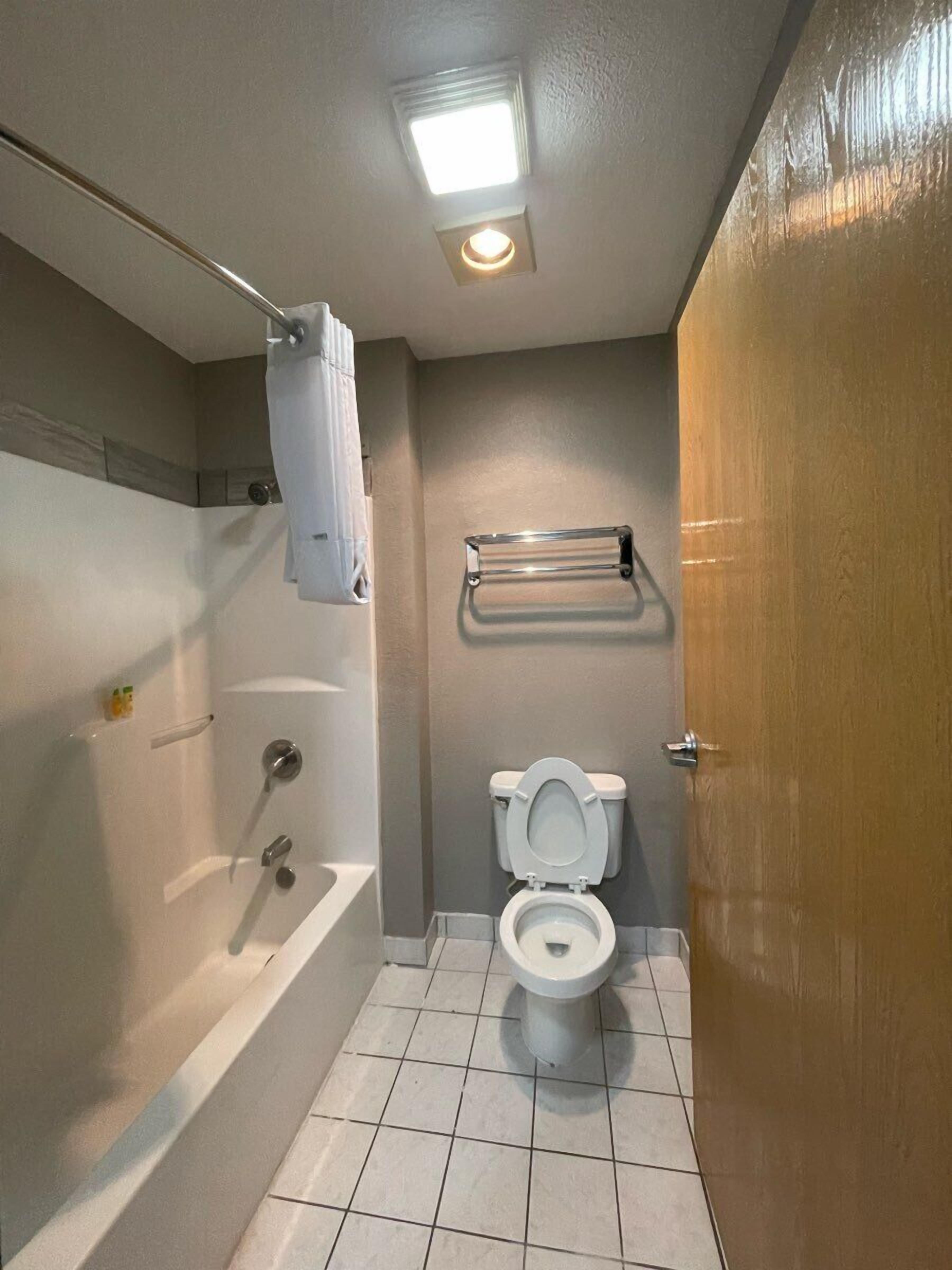 Een badkamer met een bad, toilet en douche.