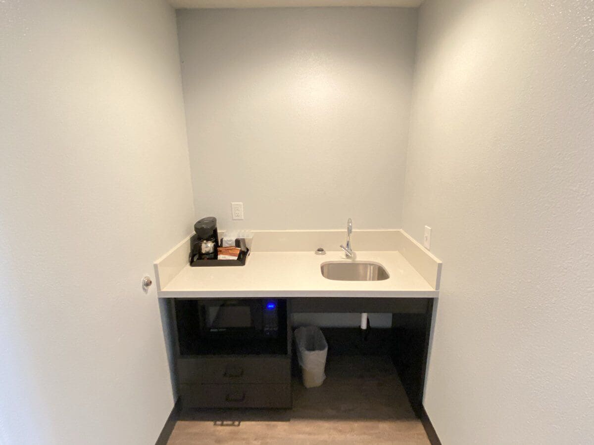 A small, white bathroom with a sink, a toilet, and a trash bin.