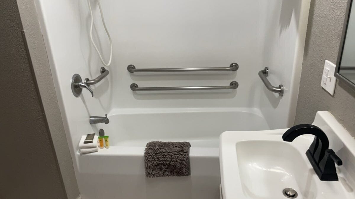 A bathroom with a bathtub, a sink, and grab bars.