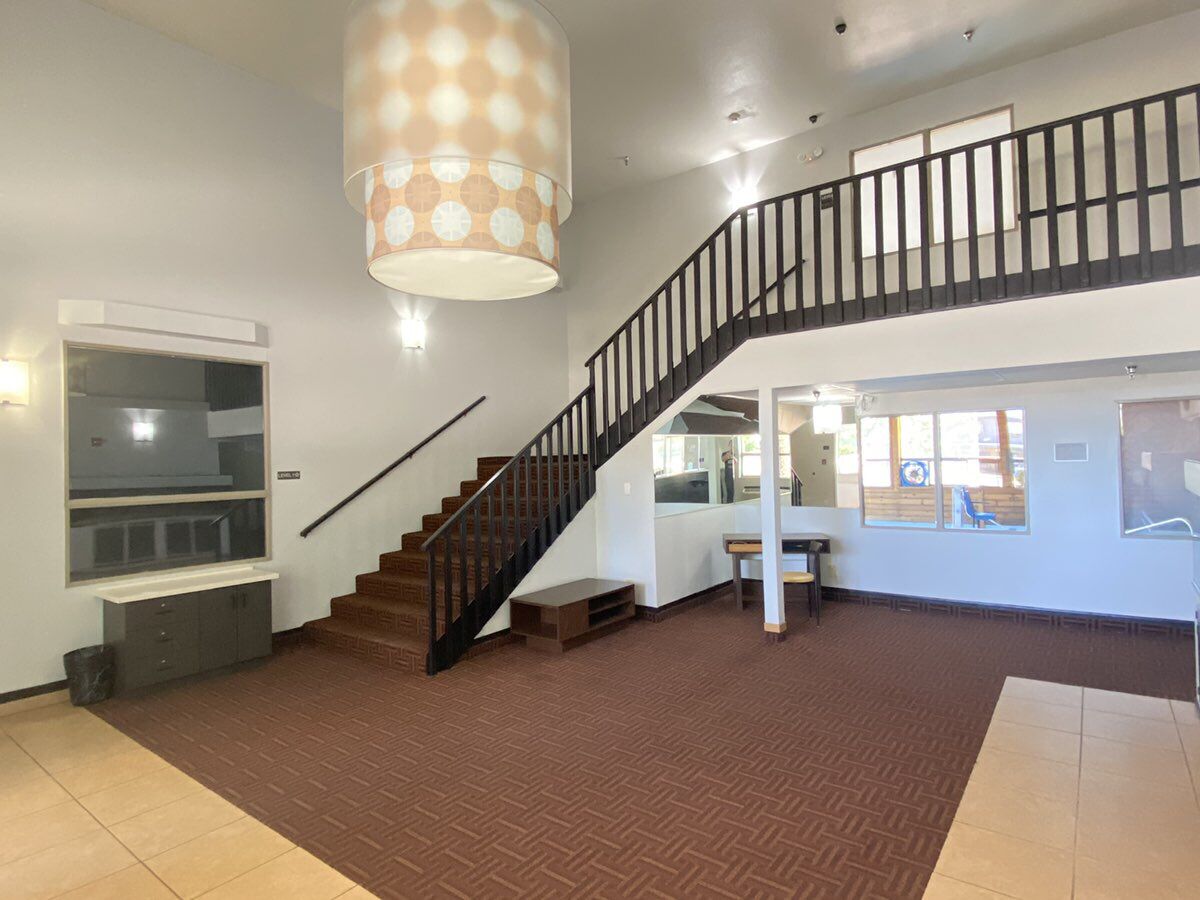 A spacious interior with a staircase, a large window, and a hanging light fixture.