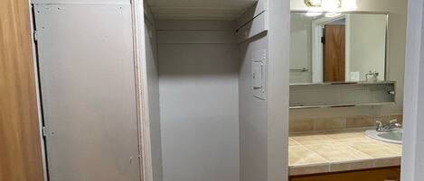 Un baño con inodoro, lavabo, espejo y un armario.