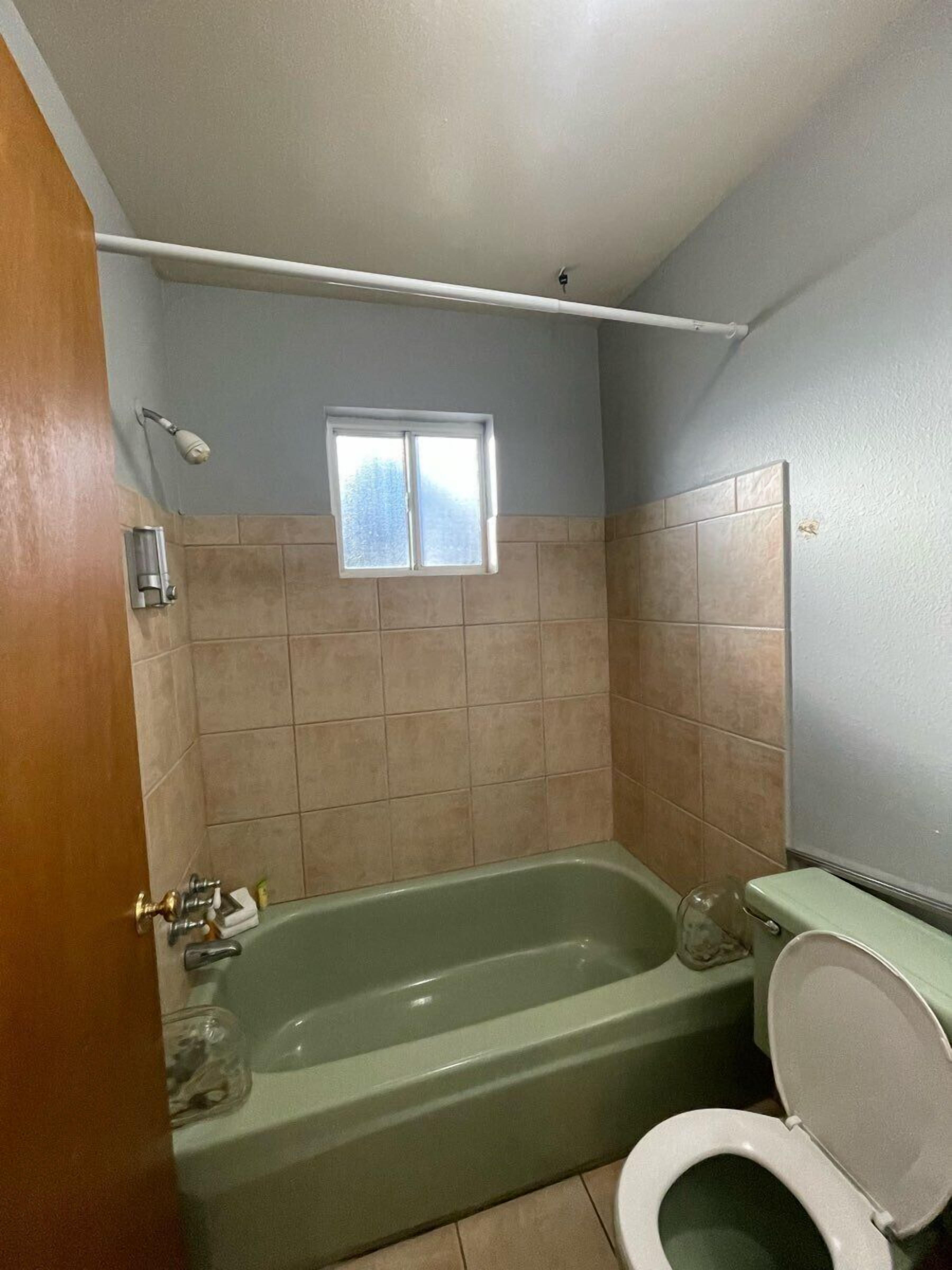 Un baño con bañera, inodoro y ventana.