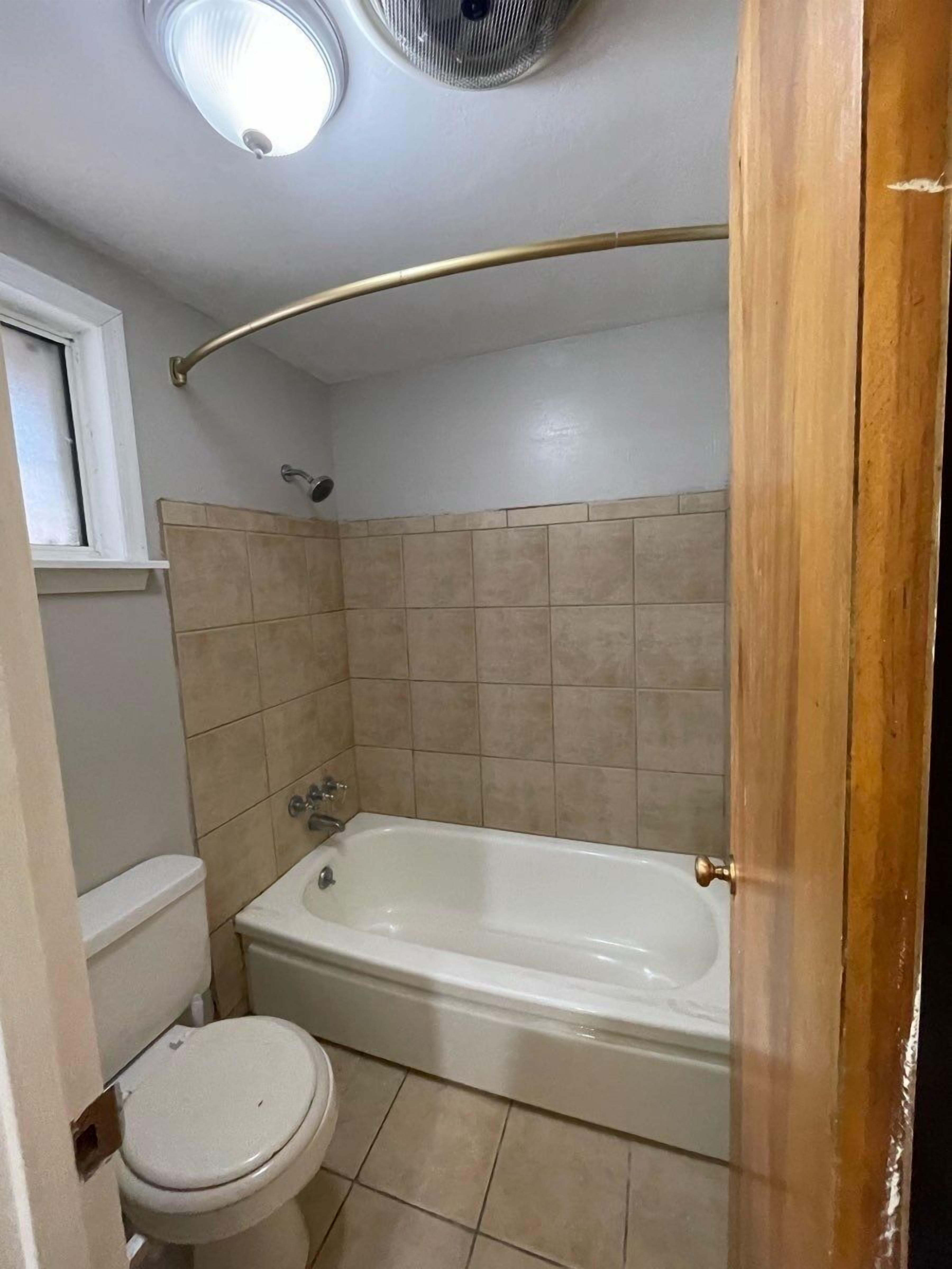 Un baño con bañera, inodoro y ventana.