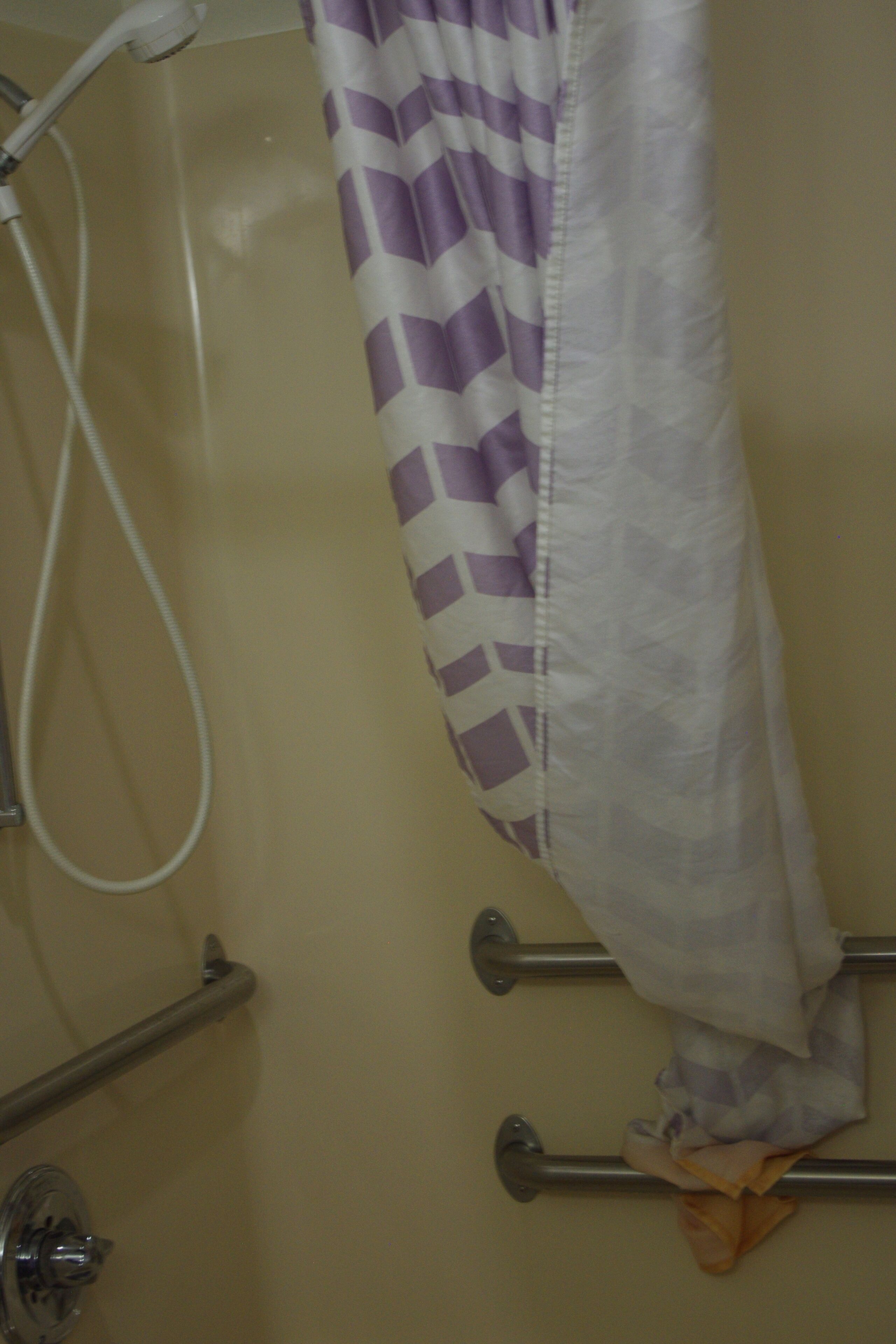 Ein Badezimmer mit Dusche, Handtuchhalter und einem waschgreifendem Duschvorhang.