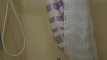 Une salle de bain avec une douche, un porte-serviettes et un rideau de douche à motifs.