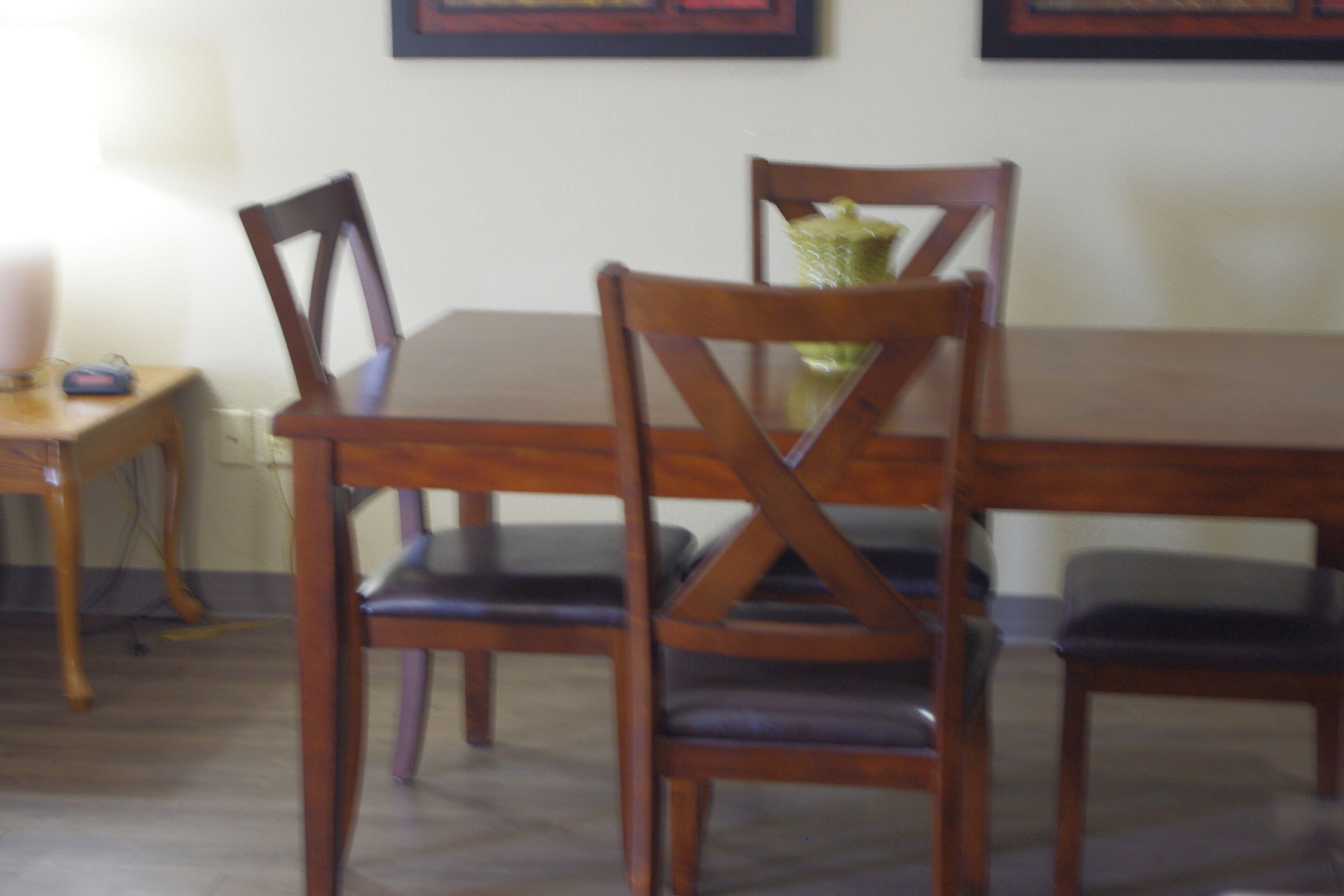 A dining table with wooden chairs and a vase with flowers.
