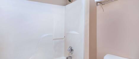 A bathroom with a white bathtub, a toilet, and a towel rack.