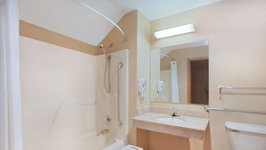 Une salle de bain équipée d’une baignoire, d’un lavabo, de toilettes et d’une douche avec des barres d’appui.