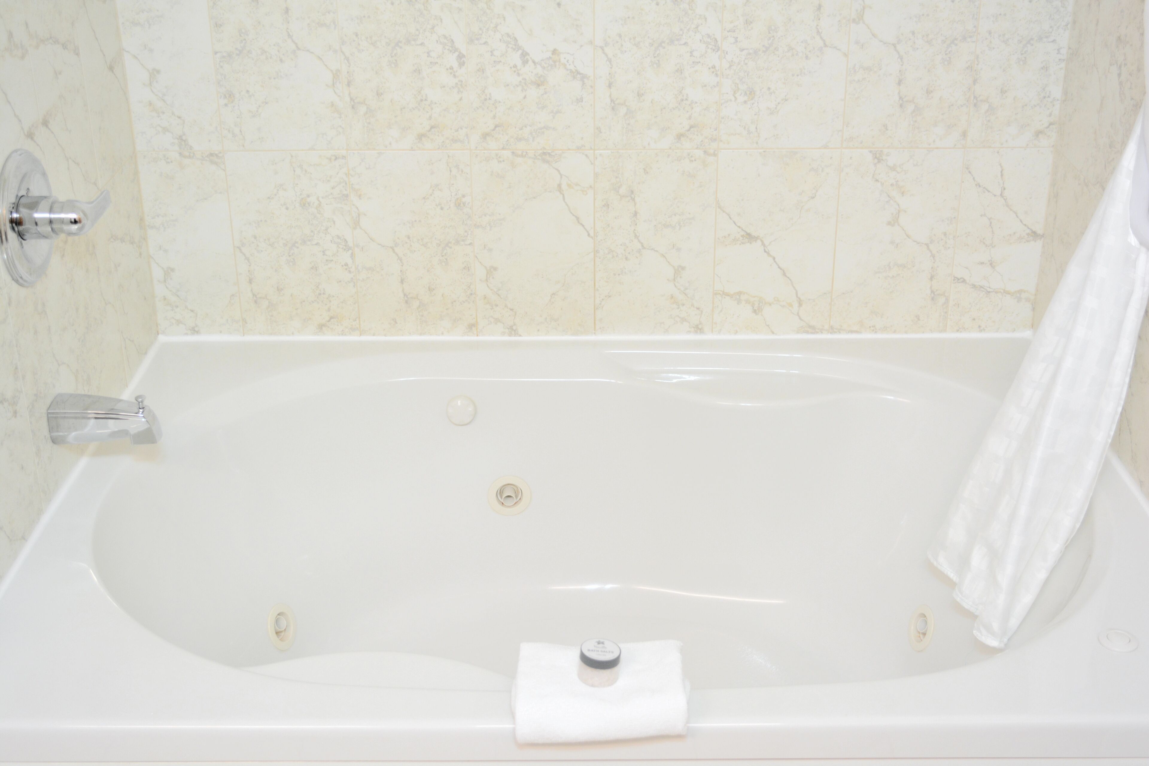 A white bathtub with a towel, a faucet, and a drain.