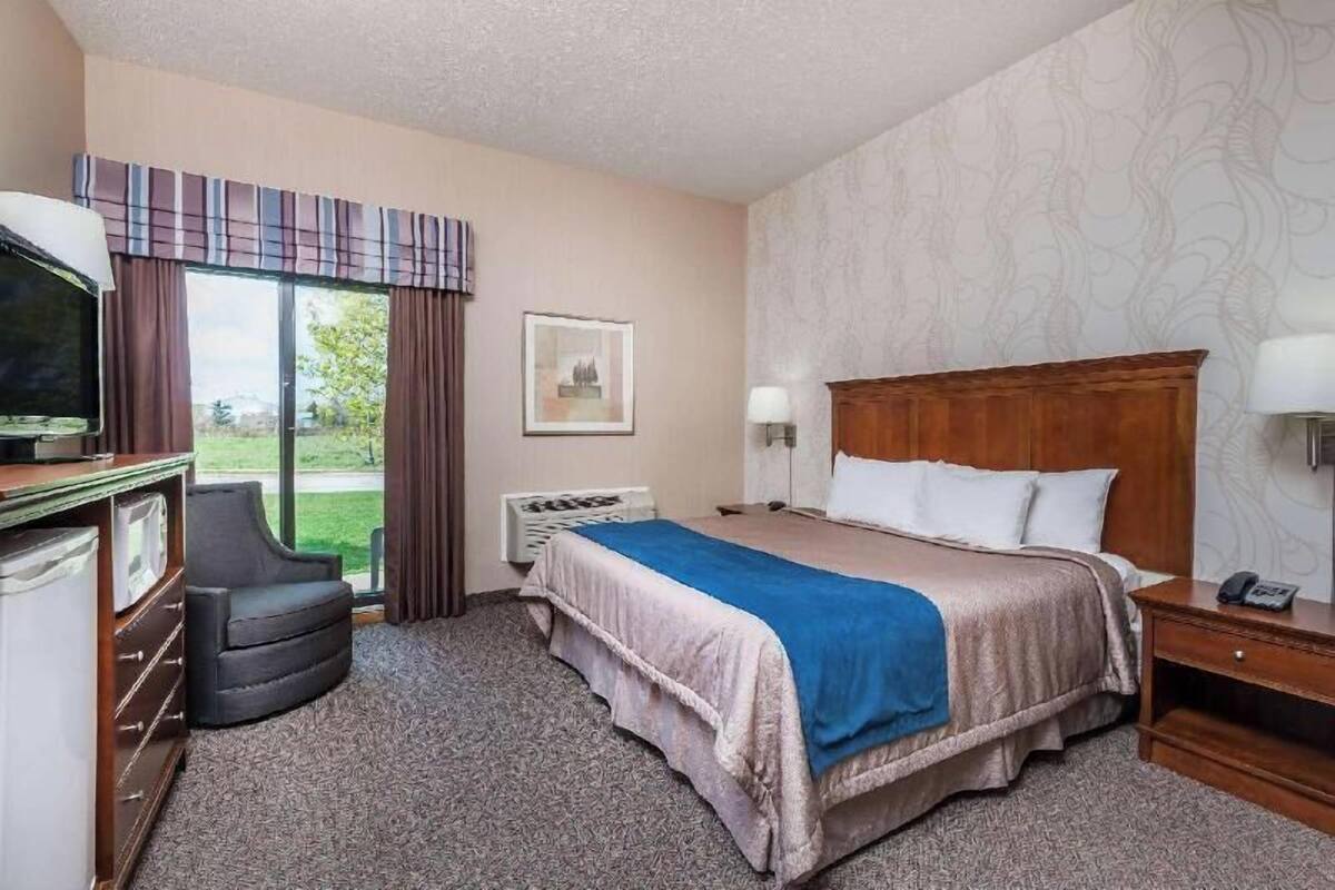 A hotel room with a bed, a desk, a chair, a television, and a window with curtains.