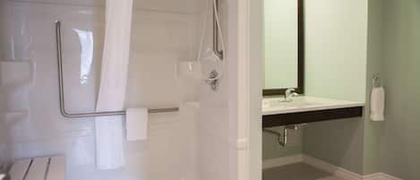 A bathroom with a shower, a sink, and a mirror.