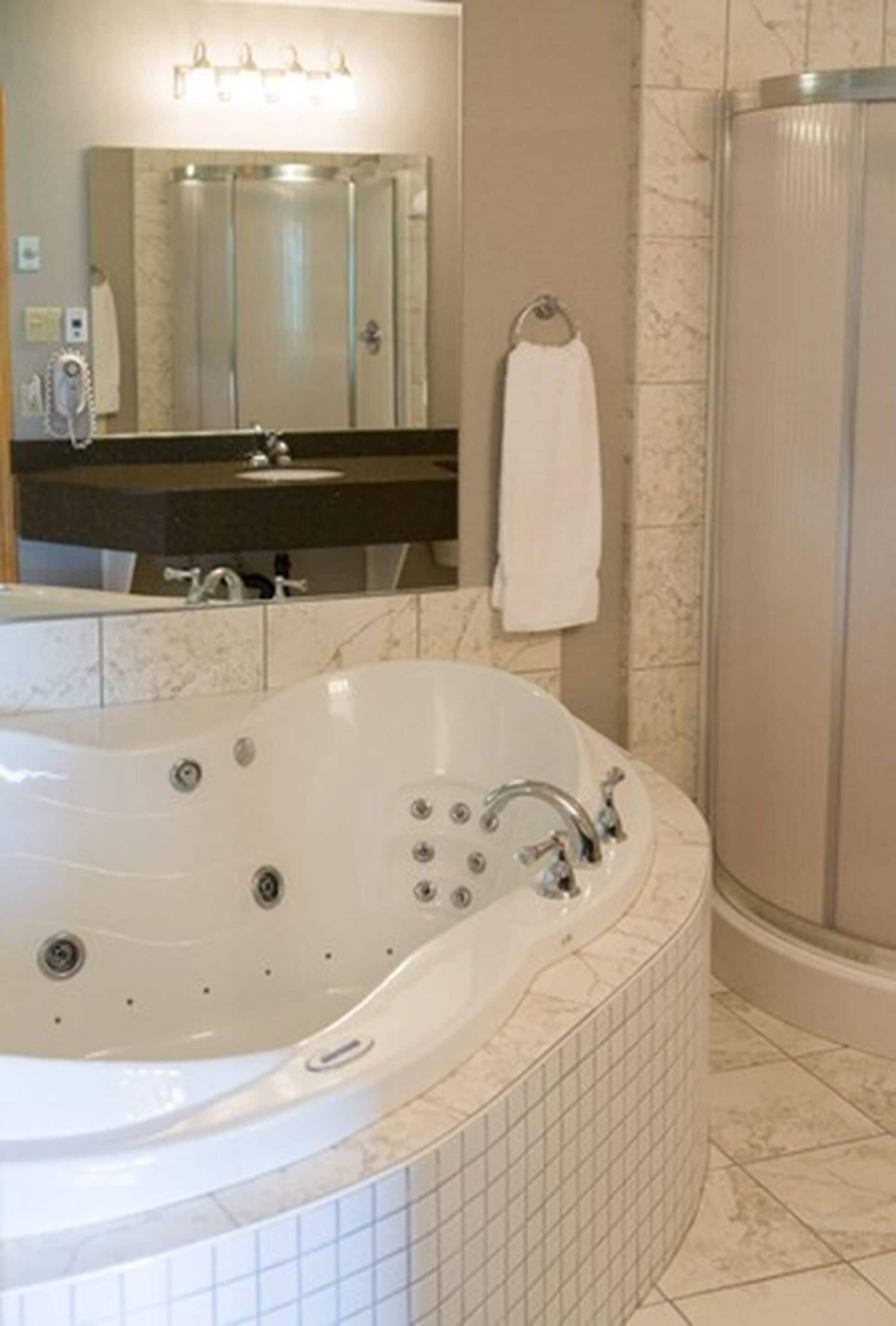 A bathroom with a large freestanding bathtub, a mirror, a towel rack, and a shower enclosure.