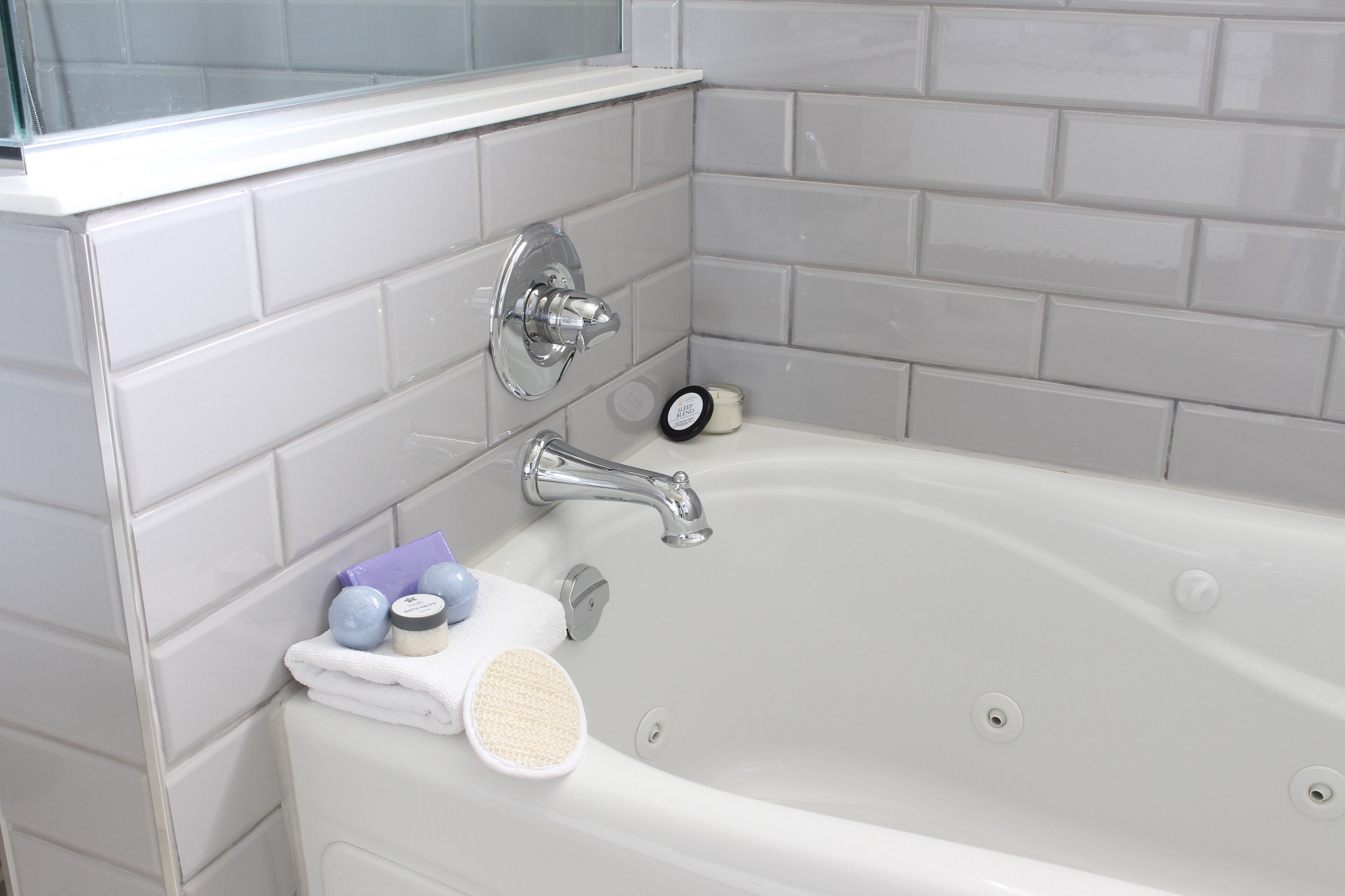 Un baño con una bañera blanca, un grifo cromado y una ventana sobre la bañera.