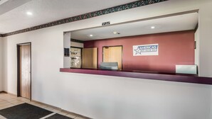 Un espace d’accueil avec un mur de couleur bordeaux, une enseigne indiquant « Americas Best Value Inn » et un comptoir de réception.