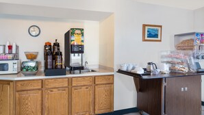 A kitchen area with a coffee machine, microwave, and various food items. - Super 8 by Wyndham Hebron Lowell Area (Hebron)