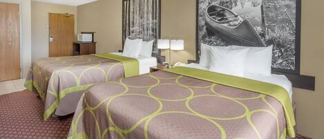 A hotel room with two beds, a wooden door, a microwave, a nightstand with a lamp, and a large painting of a boat on water.