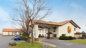 A hotel with a beige exterior, a Super 8 sign, and a parking lot with cars. - Super 8 by Wyndham Hebron Lowell Area (Hebron)