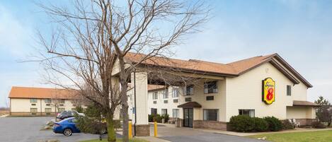 A hotel with a beige exterior, a Super 8 sign, and a parking lot with cars.
