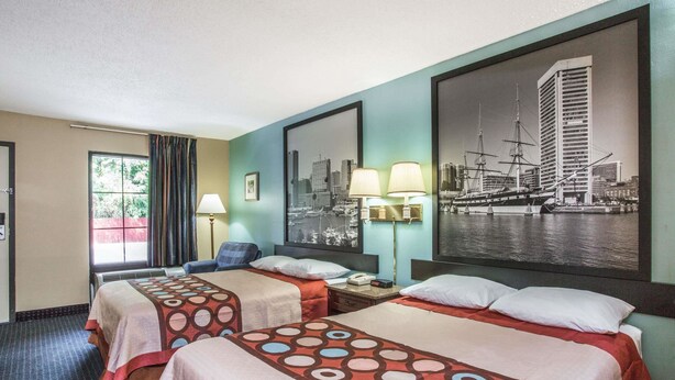 Habitación de hotel con dos camas, un cuadro de paisaje urbano y una ventana con cortinas.