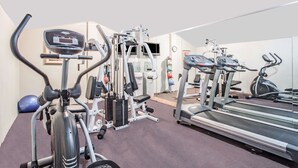 Un gimnasio con diverso equipo de ejercicio, incluyendo cintas de correr, elípticas y máquinas de pesas.
