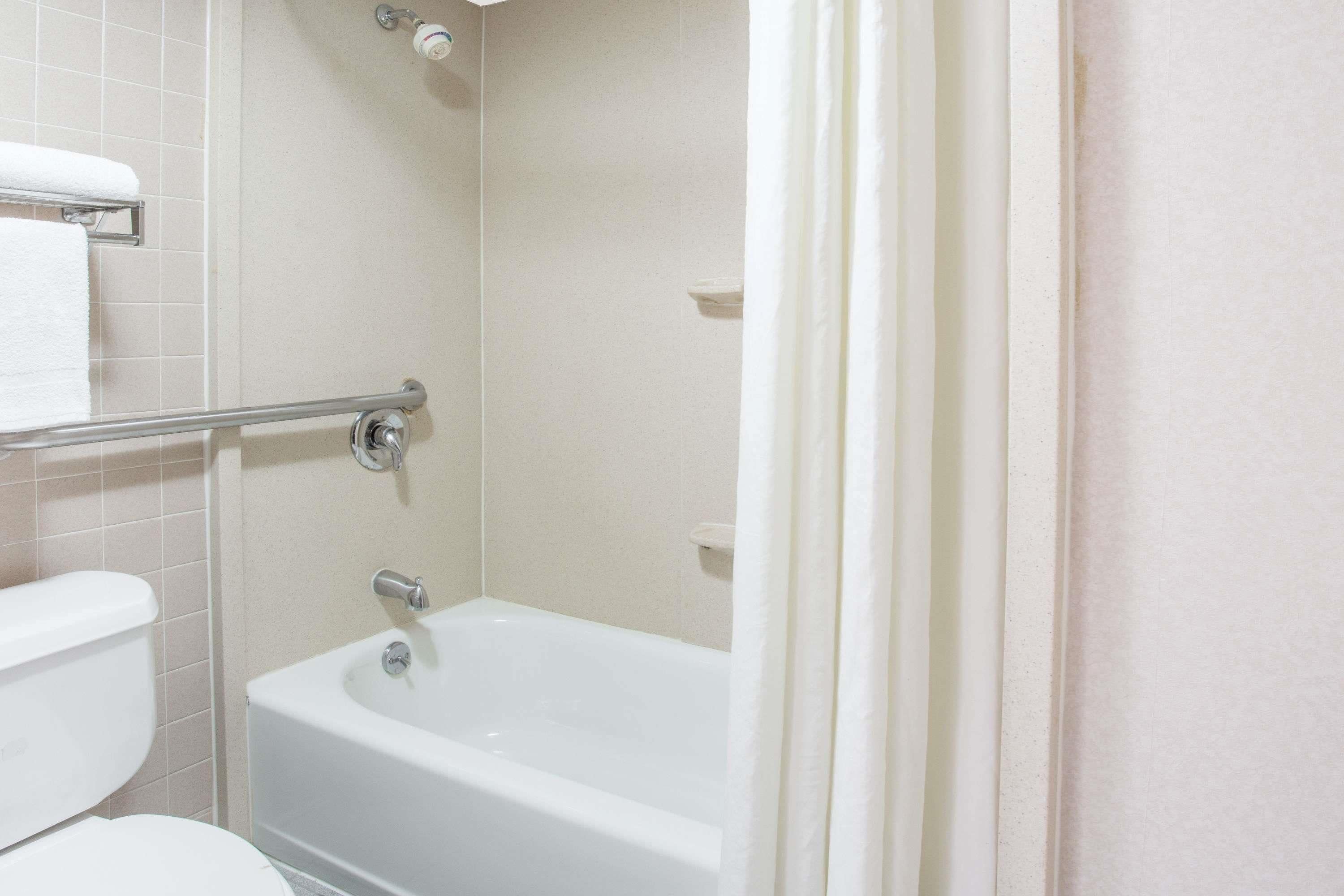 A bathroom with a bathtub, toilet, and a towel rack.